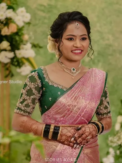 Harshitha looking happy and beautiful against a backdrop of flowers.