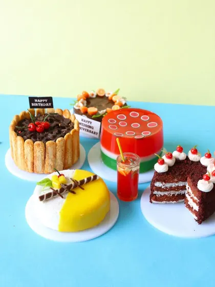 A collection of miniature cakes, including a watermelon jelly cake and a layered pastry, showing the variety of techniques taught.