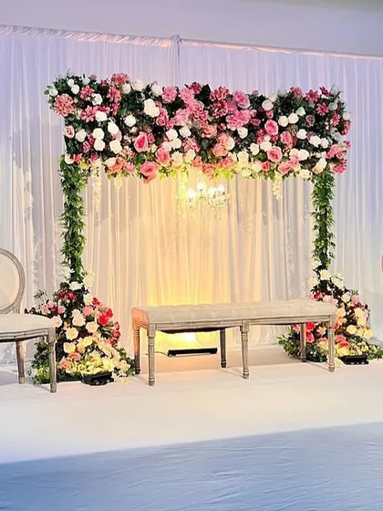 A beautiful and simple stage setup with a floral canopy. The design is perfect for an intimate engagement or reception, focusing on the beauty of the flowers.