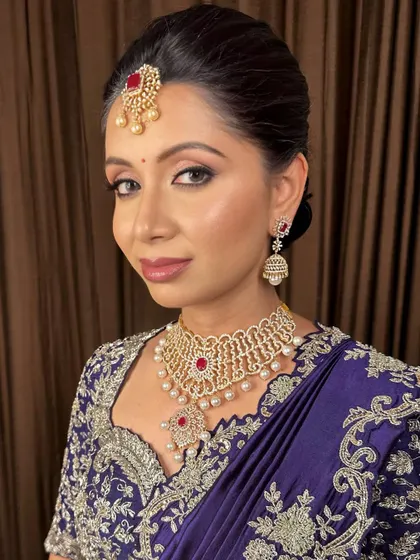 An elegant look in a deep purple saree, with sharp, defined eyes and a classic bun.