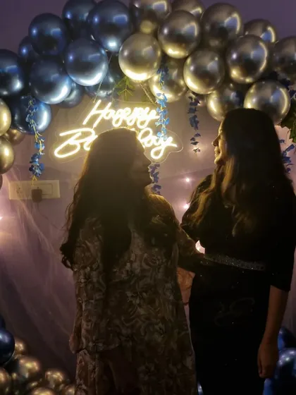 Two friends posing in front of the blue and silver birthday balloon arch. It's all about making memories with your favorite people.