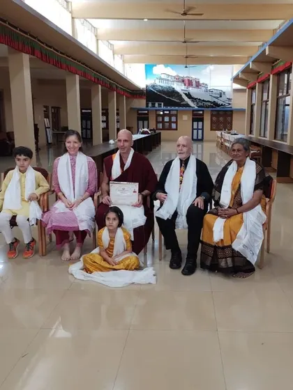 Geshe Tenzin Legtsok with community members, including a young girl seated at his feet, after the ceremony. This photo captures the warmth and accessibility of our teachers.