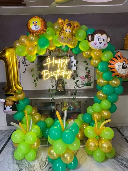 A simple yet beautiful jungle-themed balloon ring for a first birthday at home. This setup uses a neon 'Happy Birthday' sign and foil balloons of a lion, monkey, tiger, and giraffe.
