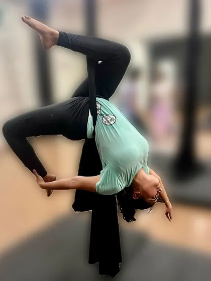 Learning to fly in an aerial hammock. This scorpion backbend variation, supported by the hammock, allows for a deeper stretch than what might be possible on the mat, improving flexibility while inverted.