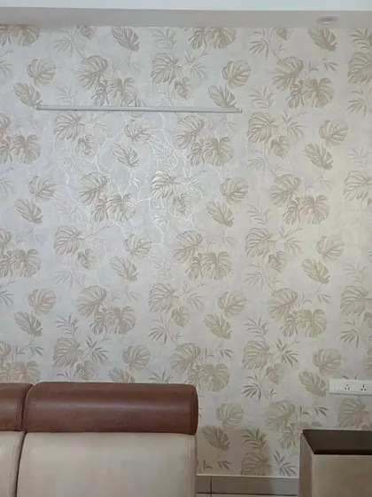 A living room with a light-colored wallpaper featuring a subtle monstera leaf pattern. The design adds texture and style without overwhelming the space.