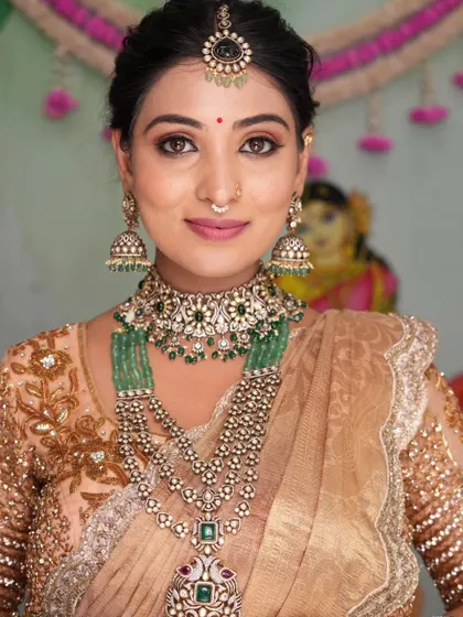 A close-up of the intricate jewellery. The combination of pearls and green stones is a classic and elegant choice.