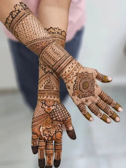 A full-hand bridal design with a mix of modern and traditional patterns. It includes a mandala on one palm and geometric grids on the other, with matching jhumka motifs.