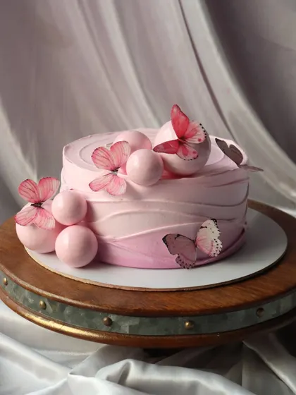 A pretty pink ombre cake decorated with pink spheres and delicate butterflies.
