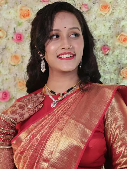 A regal reception look for Vaibhavi. Her stunning red Angadi saree is paired with a classic red lip, soft eye makeup, and loose curls for a look that is both traditional and chic.