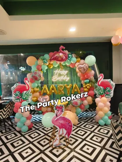 A stylish Flamingo-themed party setup in a restaurant. The tropical balloon arch, flamingo cutouts, and neon sign look fantastic against the venue's modern decor.