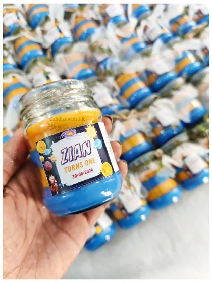 Holding one of the vibrant, layered Dragon Ball Z-themed candles, showcasing the custom sticker for Zian's first birthday.