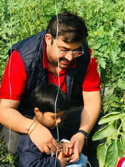 A father helps his son pick fresh tomatoes. We love seeing dads getting involved in the farm activities and creating memories with their kids.