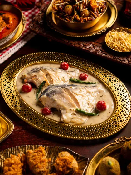 A beautifully plated fish curry from Gallops. The elegant oval dish and the creamy white gravy with pops of red and green make for a visually stunning presentation.