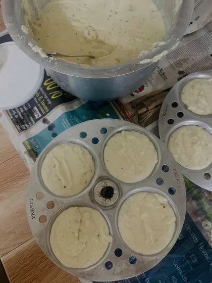 Preparing soft and fluffy idlis from our homemade batter. You can see the batter being poured into the idli stand, ready for steaming.