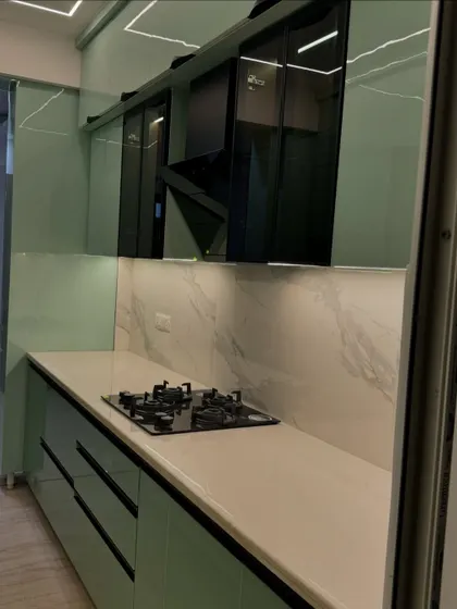 This parallel kitchen in a striking mint green high-gloss finish is both fresh and modern. The black profile handles and chimney add a bold contrast.