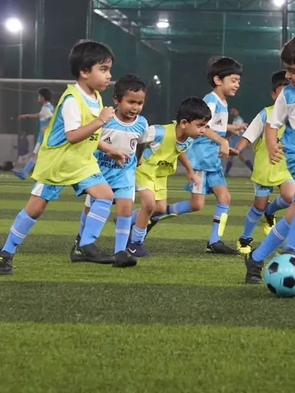 Young players in yellow and blue bibs compete for the ball during a training game.