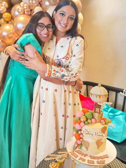 A happy moment from the celebration, with the mom-to-be and a friend posing with the custom hot air balloon cake.