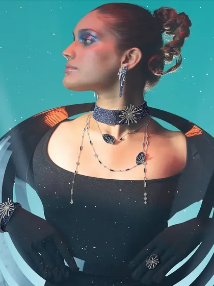 A still from the Popley jewelry campaign, showcasing the intricate, star-inspired choker, earrings, and bracelets. The styling combines a futuristic black garment with bold, blue-toned makeup.
