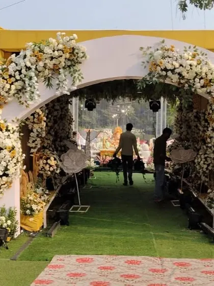 A modern and elegant entrance arch for a wedding at The Acres Club. The white structure is decorated with beautiful arrangements of white and yellow flowers.