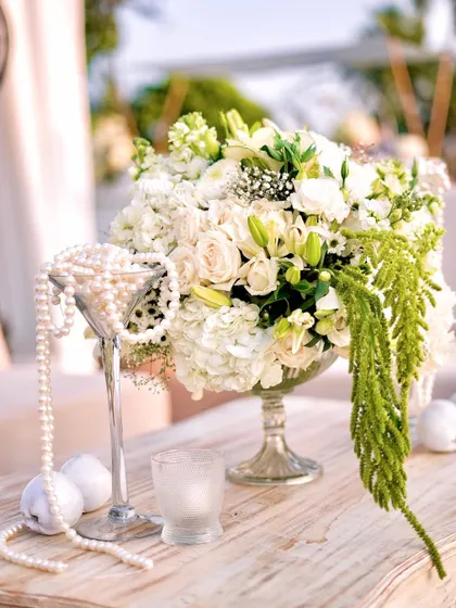 The fresh, crisp look of the white and green floral arrangement in the bright daylight. The hanging green amaranthus adds a beautiful, cascading element to the composition.
