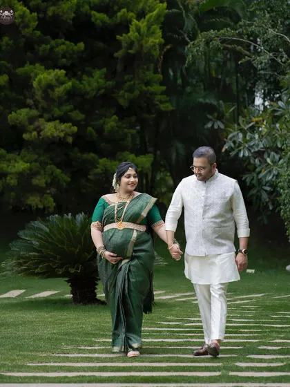 A happy couple taking a stroll through a lush garden during their outdoor maternity session. Dressed in traditional attire, this shot feels both elegant and relaxed.