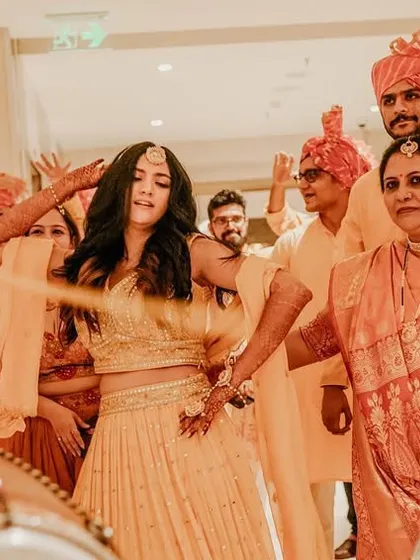 The bride dances with her family, surrounded by the energetic beats of dhol players, a classic Sangeet celebration moment.