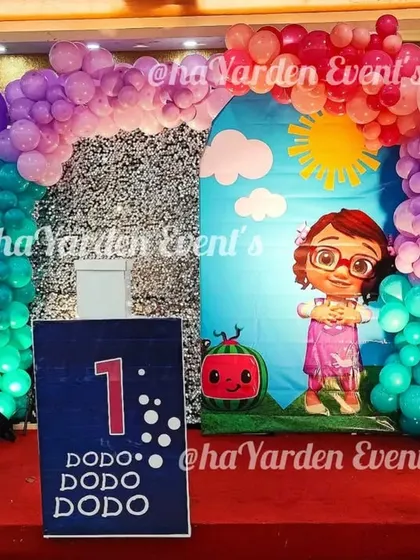 A Cocomelon and Baby Shark crossover theme, perfect for a first birthday. The stage is set with colorful backdrops and balloon columns for a fun-filled celebration.