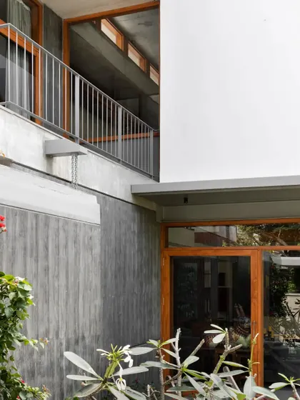 A detail showing the meeting of materials: board-formed concrete, smooth white plaster, and warm wood window frames. This honest expression of materials adds texture and character to the building's facade.