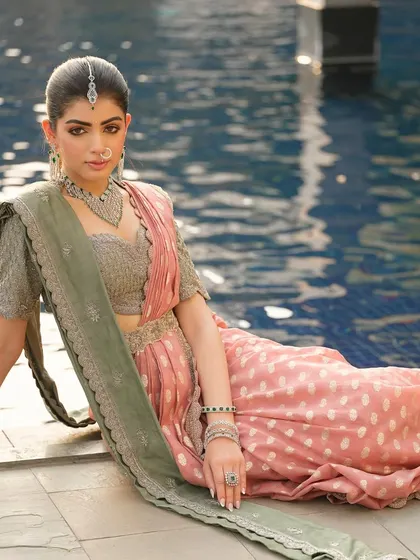 A relaxed pose by the water, showcasing the beautiful texture of the saree and the intricate details of the jewellery.