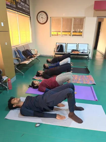A yoga session in progress, with athletes performing bridge poses to strengthen their lower back and glutes.