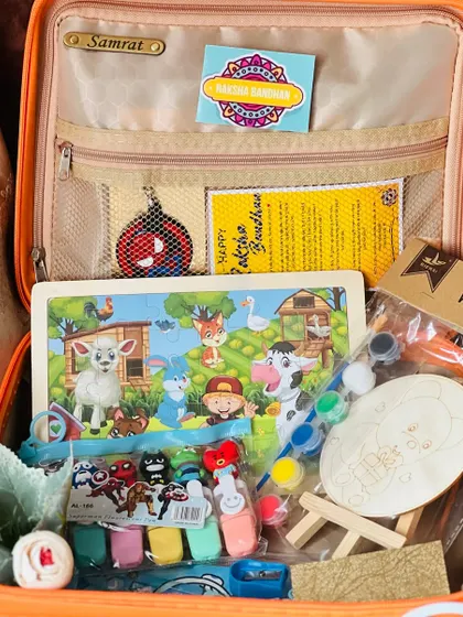 A closer look inside a kids' Rakhi hamper, showing a variety of activities like a puzzle, finger puppets, and a DIY painting kit.