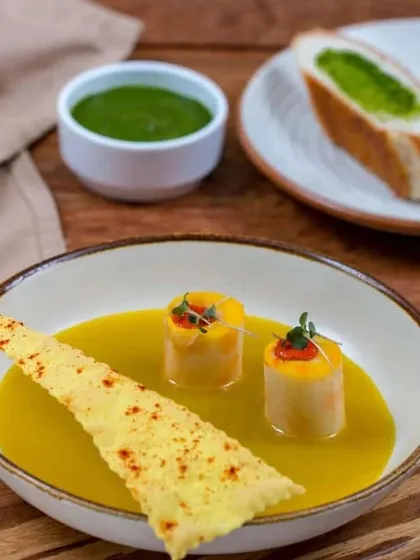 An example of our plated modern Indian cuisine. This dish features delicately prepared elements in a savory broth with a crisp wafer, showcasing our fine dining artistry.
