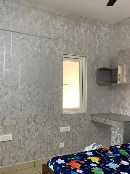 A cool, silver-grey geometric wallpaper installed in a teenager's room. The metallic finish and abstract pattern give the space a modern and grown-up feel.