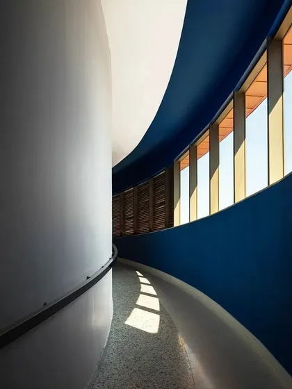 Light filters into a curved blue corridor at the MARC Auditorium, creating a serene and contemplative passage. This space demonstrates our focus on crafting atmosphere through the careful manipulation of light and form.