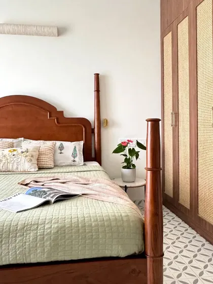 A four-poster bed is paired with a full-height wardrobe featuring wood and wicker paneling, creating a cohesive and natural look.