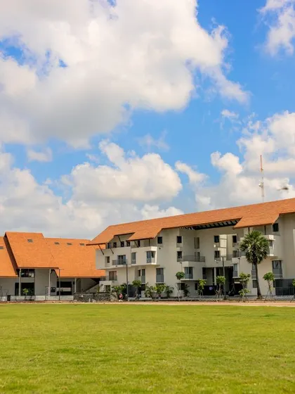 A wide view of the Vellore International School campus, showing the academic and residential blocks spread across a large, open sports field.