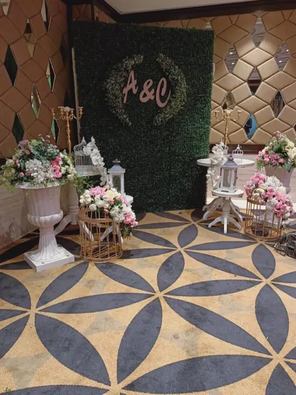 A beautiful floral setup for an engagement party, featuring a hedge wall with the couple's initials, birdcage props, and elegant flower arrangements.