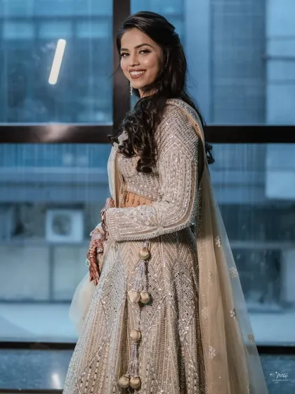 A beautiful shot of a bride in a shimmering silver-grey lehenga, perfect for an engagement or reception. The makeup is glamorous yet elegant.