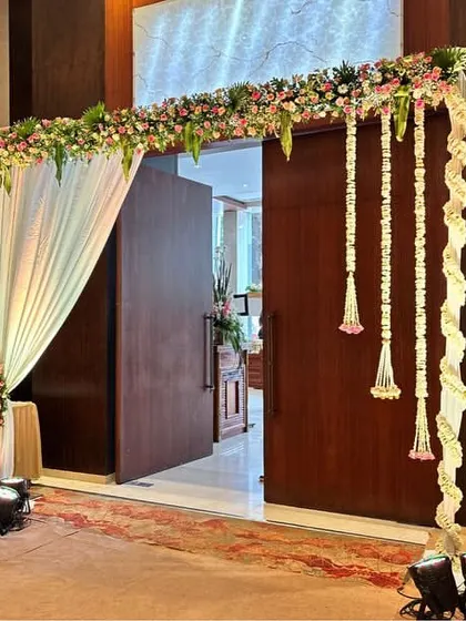 A simpler, yet elegant doorway treatment. A floral garland frames the wooden doors, with hanging tassels adding a touch of traditional charm. This is perfect for sectioning off areas within a larger venue.