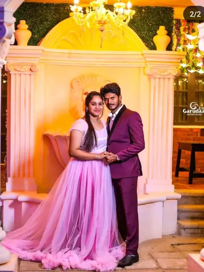 A couple poses by a fountain. The client's light pink gown with a ruffled hem creates a soft, romantic look.