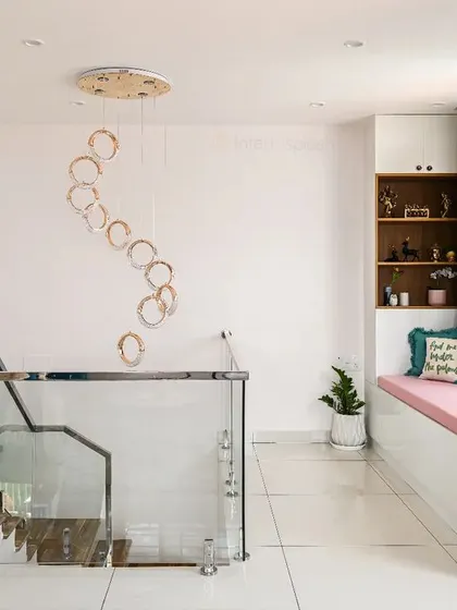 This view shows the first-floor landing with a beautiful bay window seating area. The spiral hanging light fixture is a stunning focal point that connects the two floors.