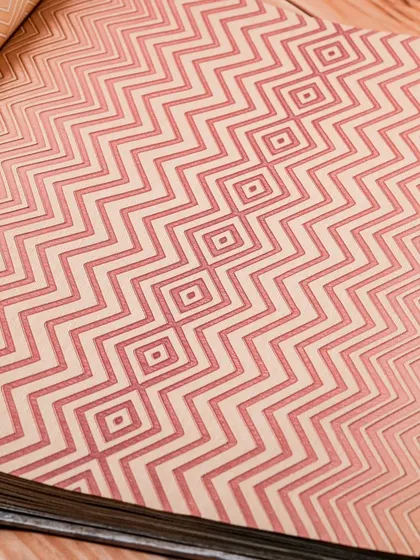 This pink and beige wallpaper features a modern chevron pattern. The geometric design is both playful and sophisticated, making it a versatile choice for a variety of spaces.