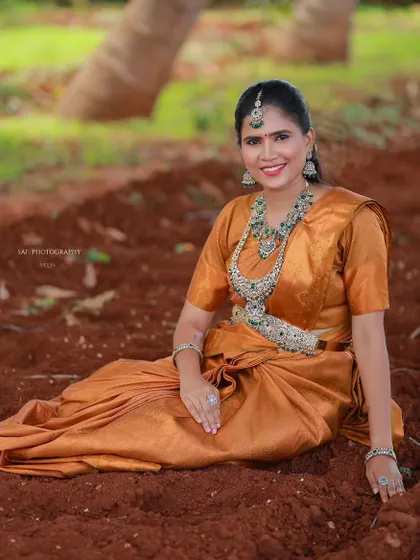 A model in a beautiful outdoor setting, wearing a full kundan and emerald stone set.
