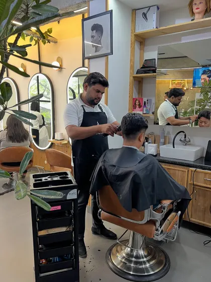A stylist focusing on a men's haircut, with our modern salon interior in the background.