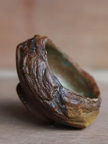 A side view of a textured, hand-built bowl. The organic creases were achieved by pushing and stretching the clay, a technique that embraces imperfection and spontaneity.
