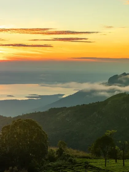 The striking Rangaswamy Peak seen from a campsite in Kodanad, Tamil Nadu. The layers of hills are shrouded in morning mist, with the sunrise painting the sky above.
