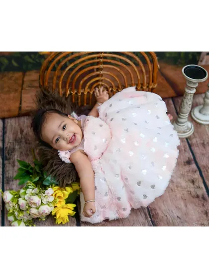 A happy baby girl lying on a wooden floor, smiling brightly for the camera during her milestone session.