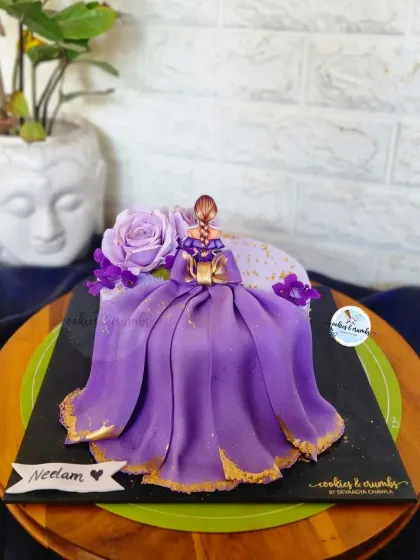 A gorgeous "Bride to Be" cake featuring a fondant doll with a flowing purple gown and gold accents. It's an elegant and personal cake for a bachelorette party or bridal shower.