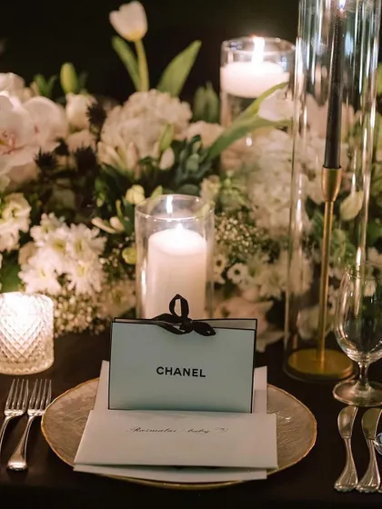 A close-up on the personalized place setting, where a Chanel favor box adds a touch of high-fashion luxury. Every detail is considered to enhance the theme and delight the guests.