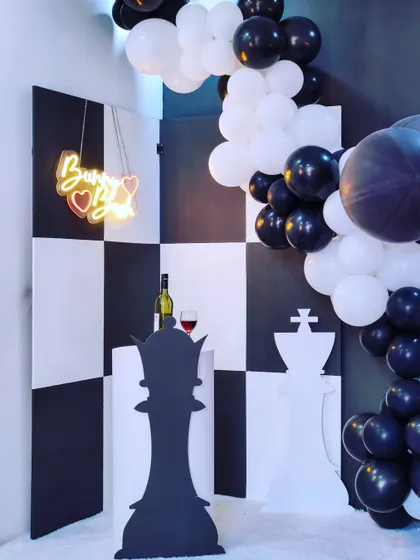This clever chess-themed decor is perfect for someone who loves strategy and style. The black and white checkerboard backdrop and giant chess piece props create a bold and unforgettable party look.